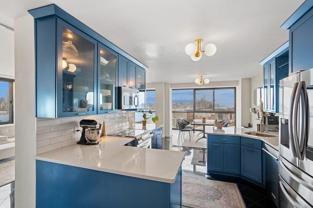 380 Mountain Rd Unit 1012, Union City, NJ 07087 - kitchen with stainless steel appliances, a peninsula, blue cabinets, tasteful backsplash, and glass insert cabinets