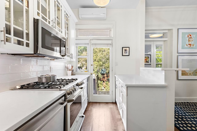 908 Garden St Unit 1, Hoboken, NJ 07030 - kitchen with stainless steel appliances, an AC wall unit, tasteful backsplash, light countertops, and crown molding
