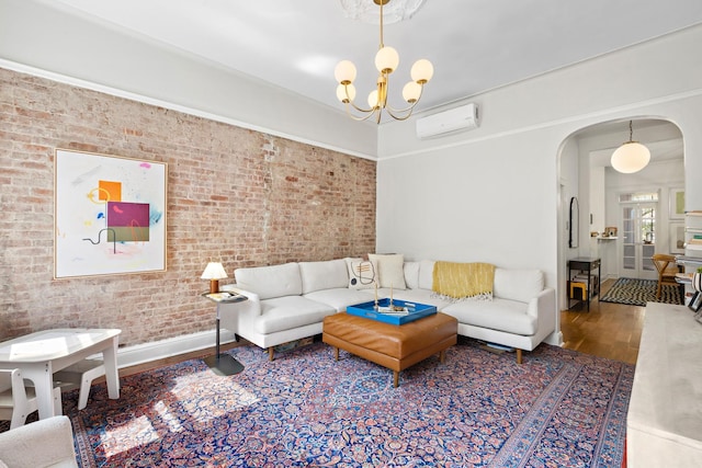 908 Garden St Unit 1, Hoboken, NJ 07030 - living room featuring an AC wall unit, arched walkways, wood finished floors, brick wall, and a chandelier
