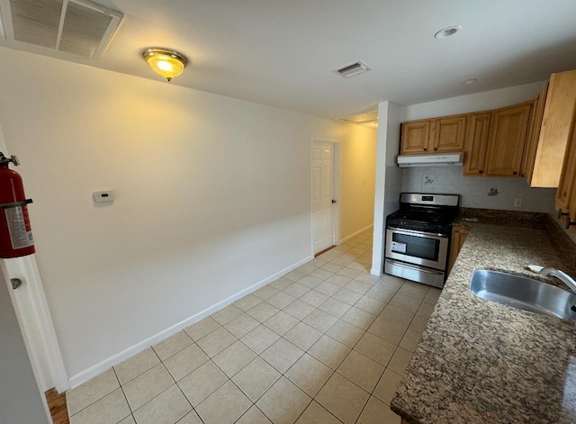 1502 44th St, North Bergen, NJ 07047 - kitchen with stainless steel range with gas cooktop, under cabinet range hood, a sink, tasteful backsplash, and light tile patterned floors