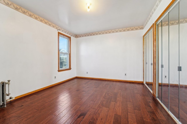 unfurnished bedroom featuring dark wood-type flooring and radiator