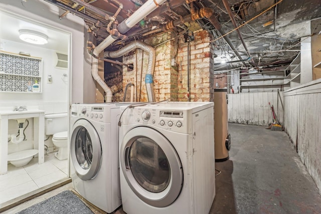 clothes washing area with separate washer and dryer and water heater