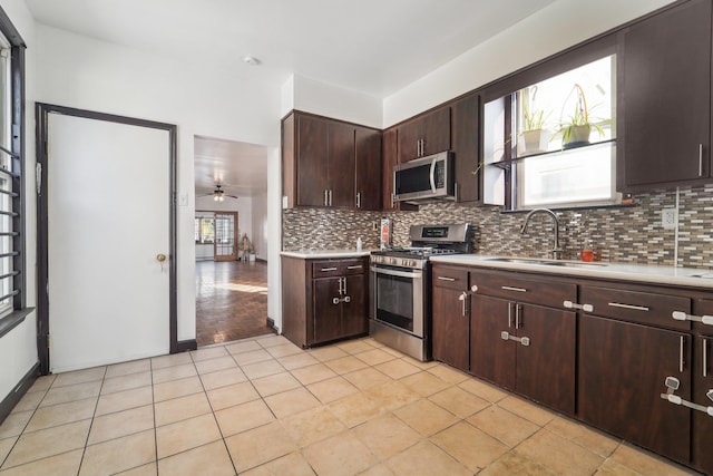 kitchen with dark brown cabinetry, ceiling fan, sink, stainless steel appliances, and backsplash