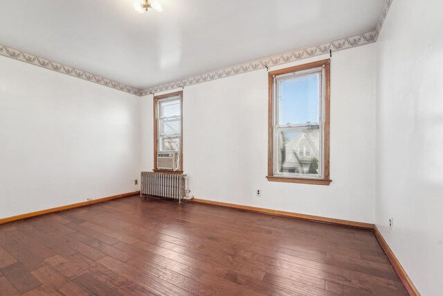 empty room featuring radiator, cooling unit, and dark hardwood / wood-style floors