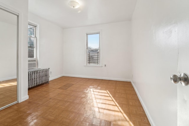 unfurnished room with radiator heating unit and parquet floors