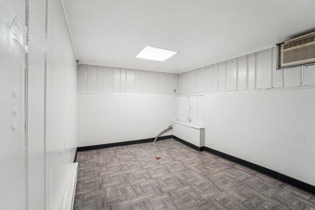 empty room with a wall unit AC and light parquet flooring