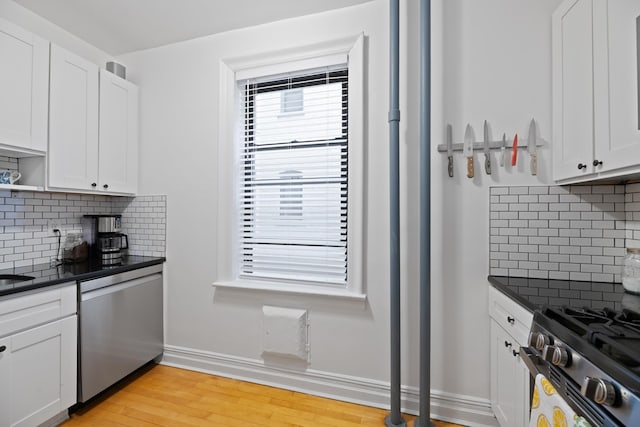 kitchen with dark countertops, light wood-style flooring, white cabinets, and stainless steel appliances