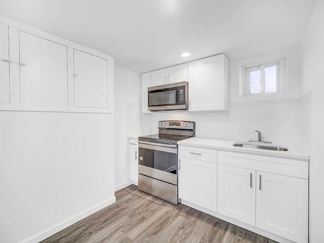 21 Freedom Pl, Jersey City, NJ 07065 - kitchen featuring appliances with stainless steel finishes, a sink, white cabinetry, light wood-style flooring, and light countertops
