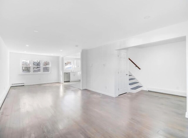 21 Freedom Pl, Jersey City, NJ 07065 - unfurnished living room featuring wood finished floors, stairway, baseboard heating, baseboards, and recessed lighting
