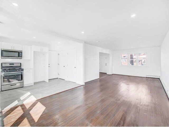 21 Freedom Pl, Jersey City, NJ 07065 - unfurnished living room with light wood-style floors, recessed lighting, baseboards, and a baseboard radiator