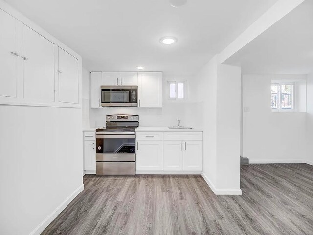 21 Freedom Pl, Jersey City, NJ 07065 - kitchen featuring appliances with stainless steel finishes, light wood-style flooring, light countertops, white cabinets, and recessed lighting