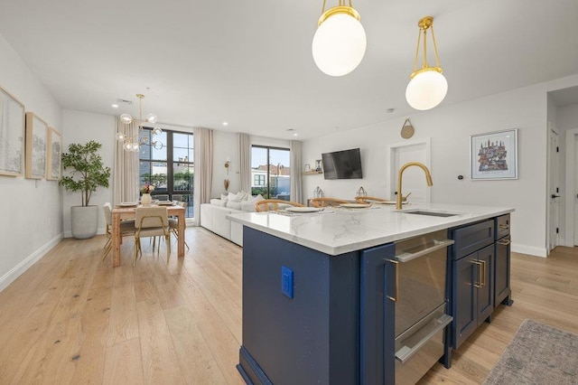 kitchen with a chandelier, pendant lighting, an island with sink, and sink