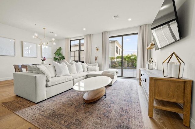 living room with light hardwood / wood-style floors and a notable chandelier