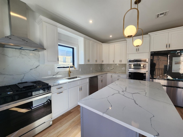 kitchen featuring pendant lighting, backsplash, wall chimney range hood, and stainless steel appliances