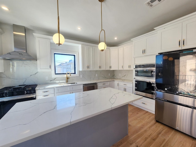 kitchen featuring white cabinetry, pendant lighting, wall chimney exhaust hood, and stainless steel appliances