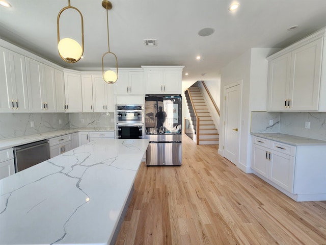 kitchen with appliances with stainless steel finishes, white cabinets, and decorative light fixtures