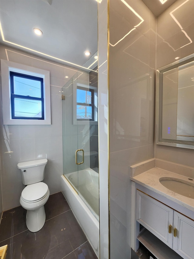 full bathroom with combined bath / shower with glass door, vanity, tile patterned flooring, and toilet