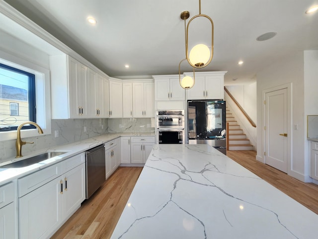 kitchen featuring tasteful backsplash, sink, white cabinetry, hanging light fixtures, and stainless steel appliances