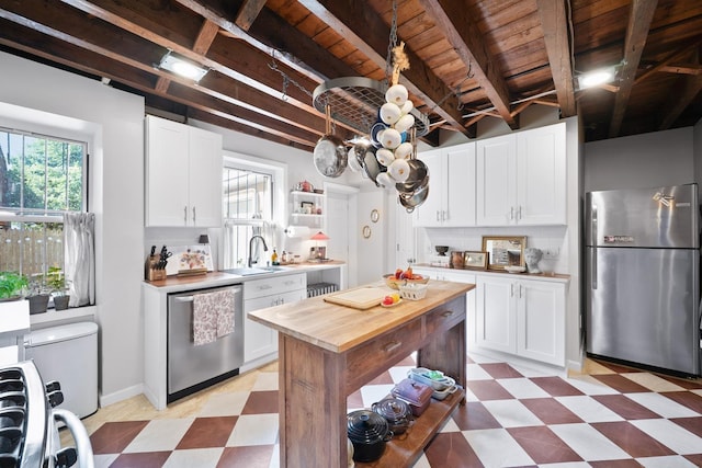 233 Summit Ave, Jersey City, NJ 07304 - kitchen with appliances with stainless steel finishes, light floors, butcher block counters, white cabinetry, and a wood ceiling with exposed beams