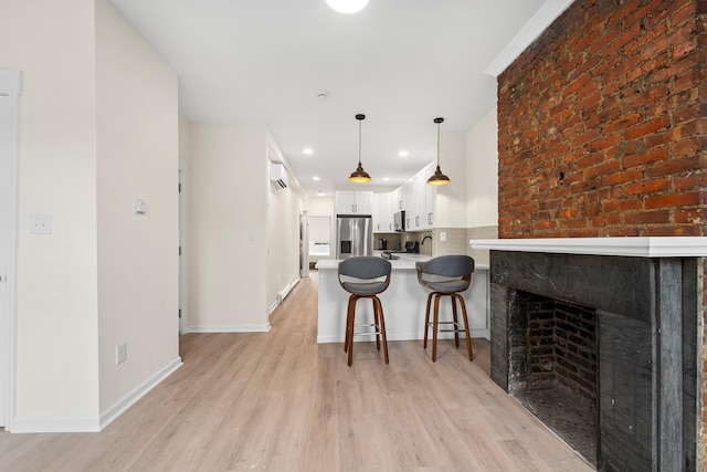 366 7th St Unit 2, Jersey City, NJ 07302 - kitchen featuring stainless steel fridge, white cabinets, light countertops, light wood-style flooring, and a kitchen breakfast bar