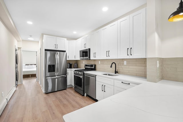 366 7th St Unit 2, Jersey City, NJ 07302 - kitchen with appliances with stainless steel finishes, stacked washer / drying machine, light wood-style flooring, white cabinets, and recessed lighting