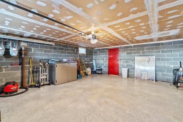 garage with a garage door opener and concrete block wall