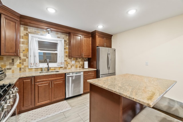 kitchen featuring a kitchen bar, a sink, light stone counters, backsplash, and stainless steel appliances