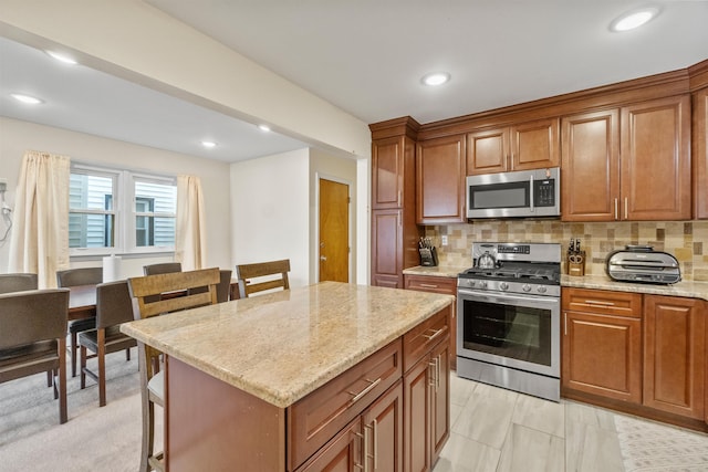 kitchen featuring brown cabinetry, light stone countertops, tasteful backsplash, and appliances with stainless steel finishes