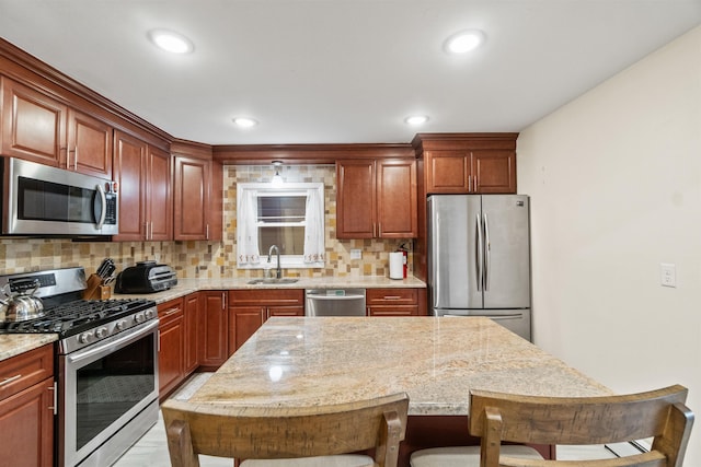 kitchen with a kitchen island, a sink, appliances with stainless steel finishes, a kitchen bar, and tasteful backsplash