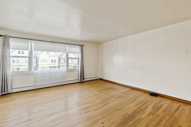 spare room with light wood-type flooring, a baseboard heating unit, and baseboards