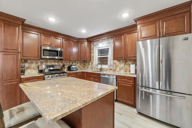 kitchen featuring backsplash, light stone counters, a kitchen breakfast bar, stainless steel appliances, and a sink