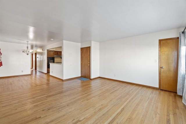 unfurnished living room with baseboards, light wood-type flooring, and an inviting chandelier