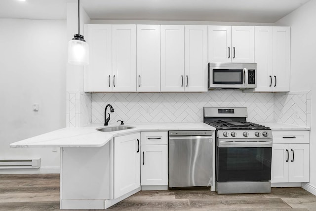 609 New York Ave Unit 2L, Union City, NJ 07087 - kitchen with appliances with stainless steel finishes, a baseboard radiator, white cabinets, light wood-style flooring, and tasteful backsplash
