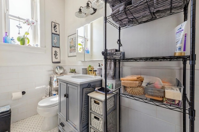 bathroom featuring toilet, tile patterned flooring, tile walls, and vanity