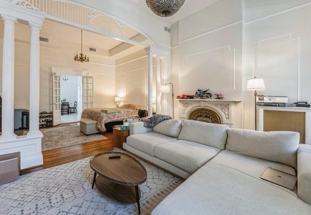 living room with ornate columns, a towering ceiling, and wood-type flooring