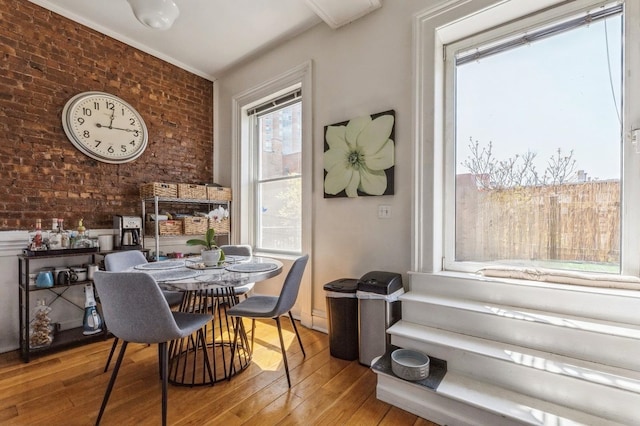 dining area with brick wall and hardwood / wood-style floors