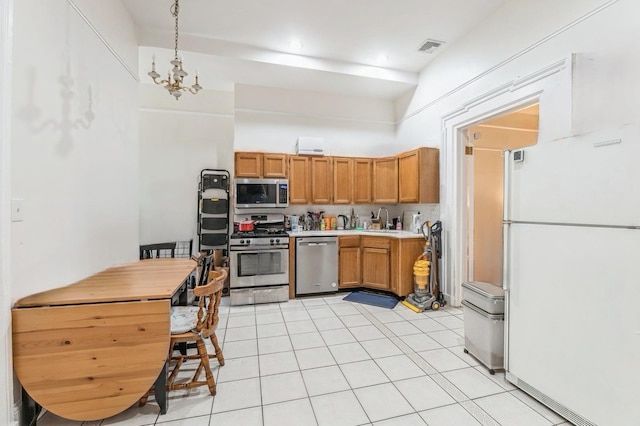 kitchen featuring a high ceiling, stainless steel appliances, sink, hanging light fixtures, and light tile patterned flooring