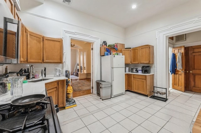 kitchen featuring light tile patterned flooring, sink, white refrigerator, and tasteful backsplash