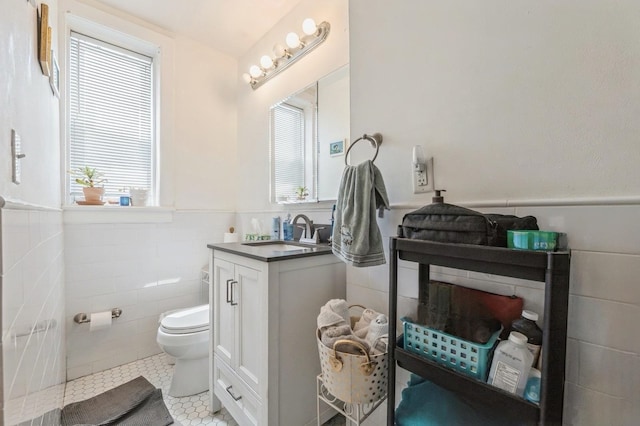 bathroom featuring toilet, vanity, tile walls, and tile patterned floors