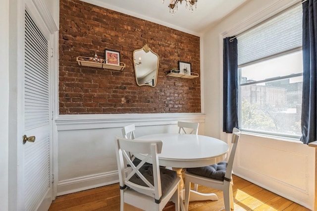 dining room with wood-type flooring and brick wall