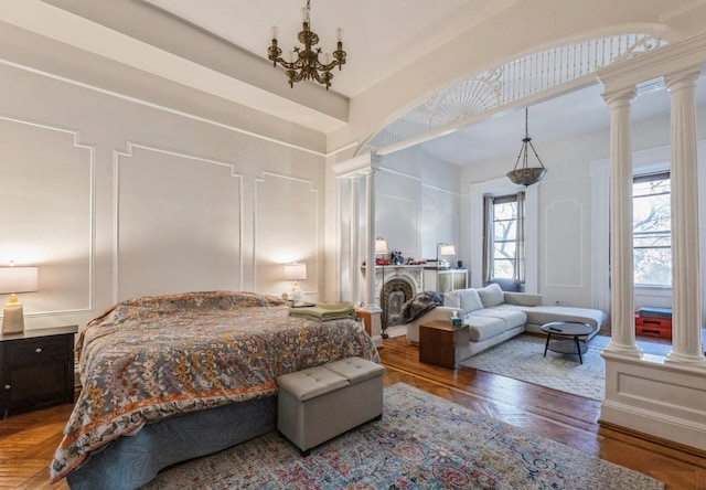 bedroom with ornate columns and a chandelier