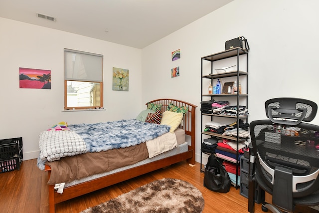 bedroom featuring wood finished floors, visible vents, and baseboards