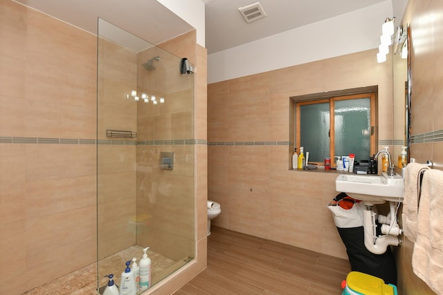 full bath featuring visible vents, tile walls, and a walk in shower