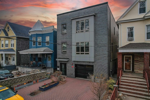 view of front facade featuring decorative driveway, brick siding, and an attached garage