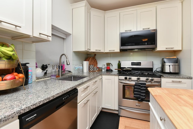 kitchen with backsplash, appliances with stainless steel finishes, wooden counters, and a sink