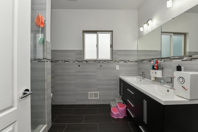 bathroom with tile patterned flooring, visible vents, a sink, and tile walls