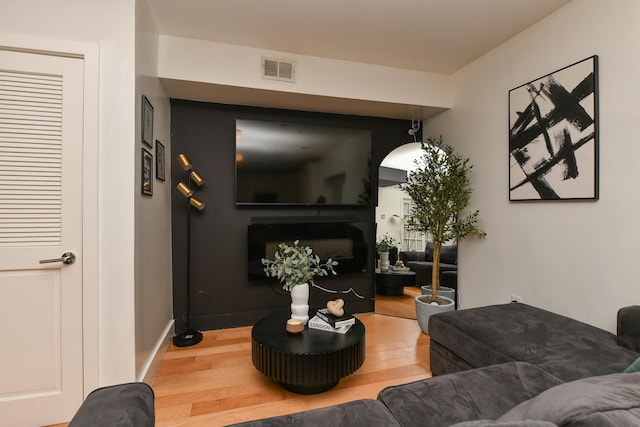 living room featuring a fireplace, wood finished floors, visible vents, and baseboards