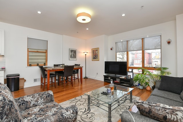 living room with baseboards, visible vents, wood finished floors, and recessed lighting