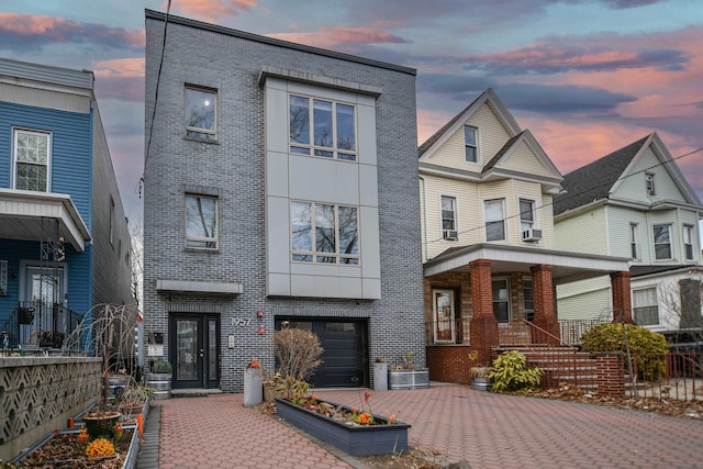 view of front of house with brick siding, decorative driveway, an attached garage, and fence