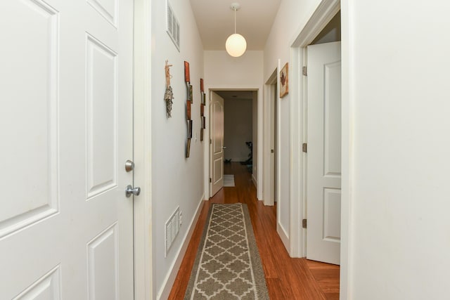 corridor with wood finished floors, visible vents, and baseboards